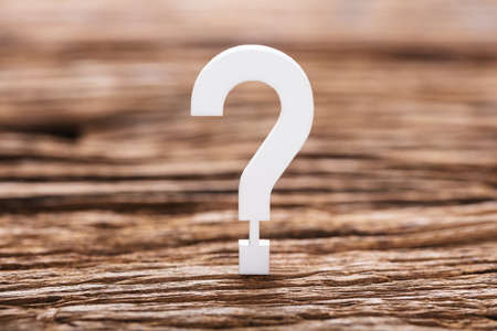 Close-up Of A White Question Mark Sign On Wooden Tableの写真素材