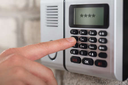 Close-up Of A Person's Hand On Security Alarm Keypad Entering The Security Code