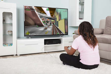 Rear View Of An African Girl Playing Video Games At Home