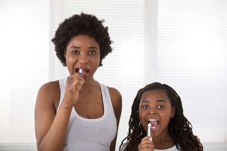 African Mother And Daughter Brushing Their Teeth In The Bathroom