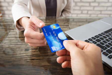 Hand Of A Person Giving Debit Card To Businesswoman At Workplace In Officeの写真素材