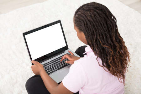 A Girl Sitting On Carpet Using Laptop With Blank Screen