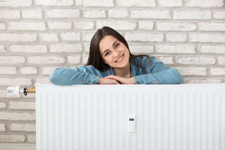 Portrait Of A Smiling Woman Behind The Heating Radiatorの写真素材