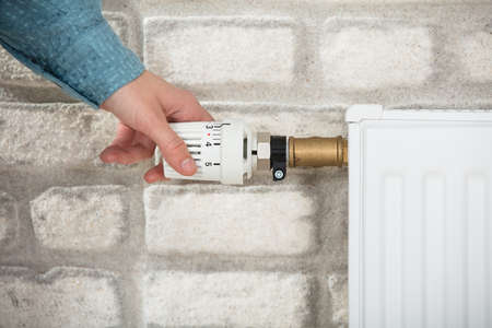 Close-up Of A Person's Hand Adjusting Temperature Of Radiator Thermostat