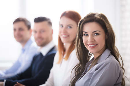 Portrait Of Young Smiling Businesswoman With Her Colleagues In Officeの写真素材