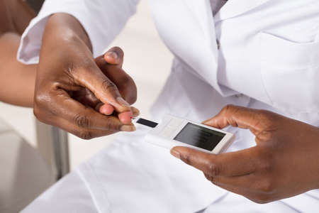 Close-up Of A Doctor Checking Patient's Sugar Level With Glucometerの写真素材