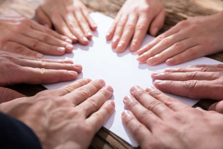 Close-up Of Hands Touching White Paper Over The Wooden Desk Showing Team Concept