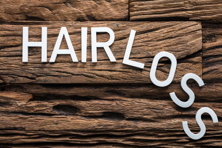 Closeup of white hair loss text on wood