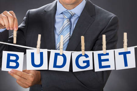 Closeup midsection of businessman pinning BUDGET cards on clotheslineの写真素材