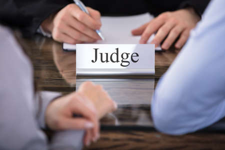 Close-up Of A Judge With The Name Plate Engraving Judge On Desk