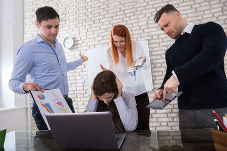 Depressed young businesswoman pressured by her colleague in office
