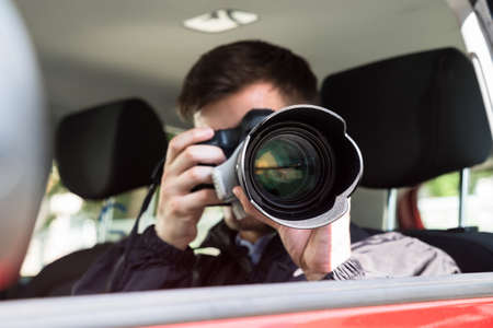Side View Of A Private Detective Sitting Inside Car Photographing With Slr Cameraの写真素材