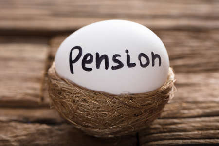 Closeup of pension written on white egg in nest on wood
