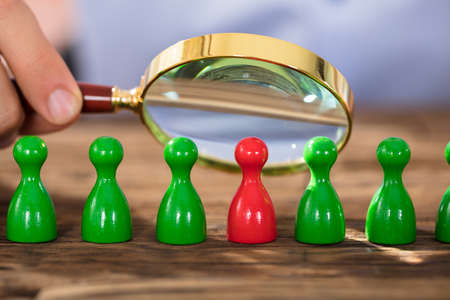 Close-up Of A Person Examining The Plastic Figures With Magnifying Glass Over The Tableの写真素材