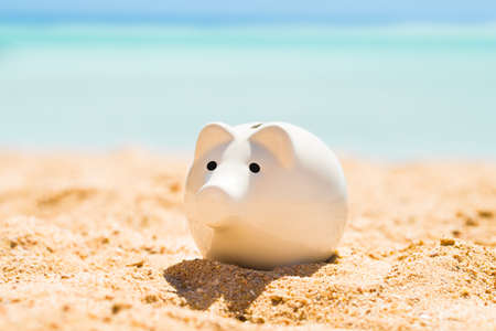 A White Piggy Bank On Sand At Beach In Summerの写真素材