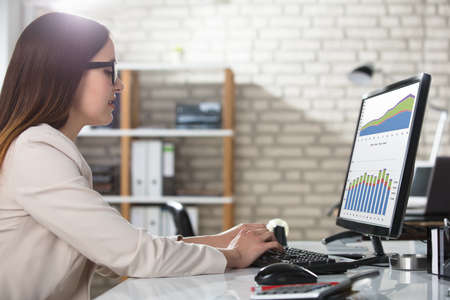 Young Smart Businesswoman Analyzing Graph On Computer In Officeの写真素材