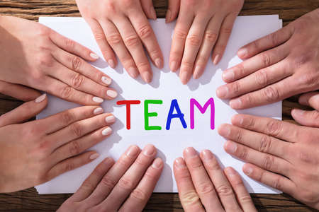 Elevated View Of Hands Touching The White Paper With Colorful Word Team Written On It