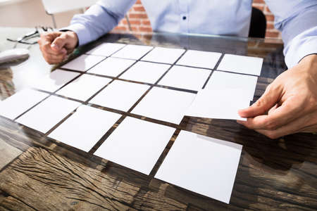 Close-up Of A Businessman Arranging White Adhesive Notes On Glass Desk In Officeの写真素材