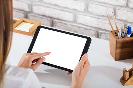 Close-up Of A Person's Hand Using Digital Tablet With Blank White Screenの写真素材