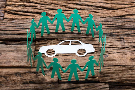 High angle view of green paper team surrounding car on wooden tableの写真素材