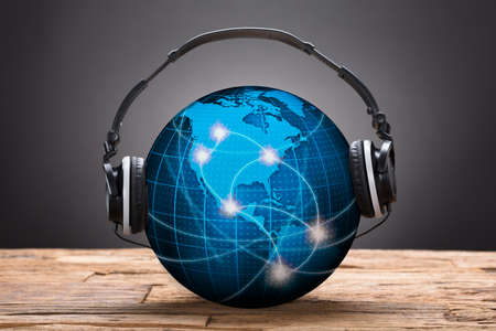 Closeup of headphones on blue globe against black backgroundの写真素材