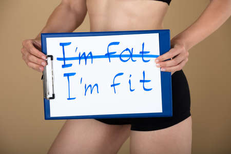 Healthy Woman Holding Clipboard With I'm Fat And I'm Fit Message Textの写真素材