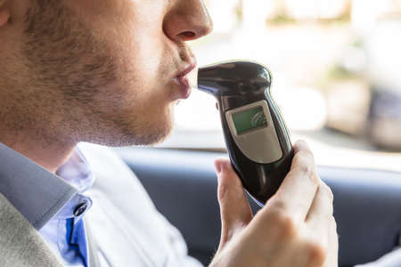 Close-up Of A Young Man Sitting Inside Car Taking Alcohol Testの写真素材