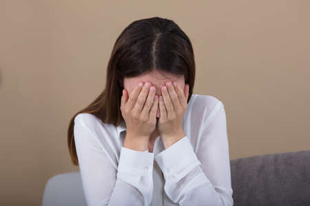 Close-up Of A Tensed Woman Covering Her Face At Home