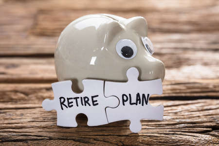 Closeup of connected retire plan jigsaw pieces by piggybank on woodの写真素材