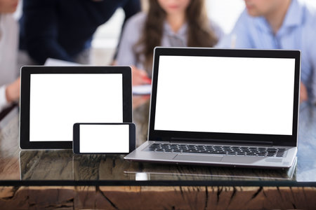 Modern Electronic Devices On Office Desk With Businesspeople At Backgroundのeditorial素材