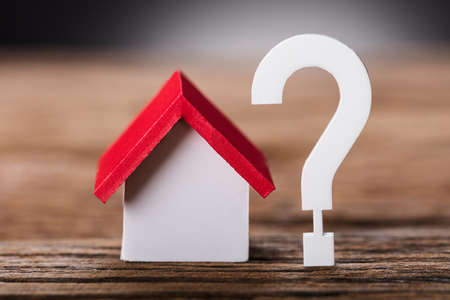 Closeup of small model house by question mark on wooden tableの写真素材