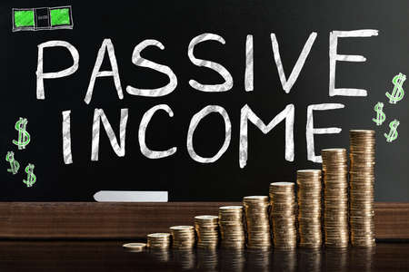 Passive Income Word On Blackboard Behind Stacked Coinsの写真素材