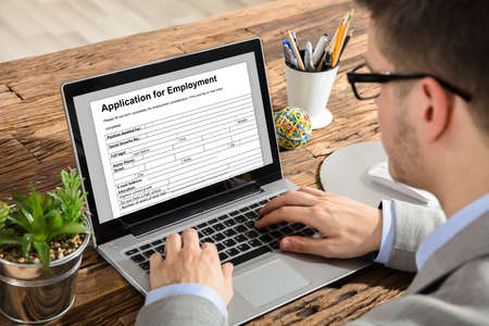 Close-up Of A Young Businessman Filling Application For Employment Form On Laptop At Workplace