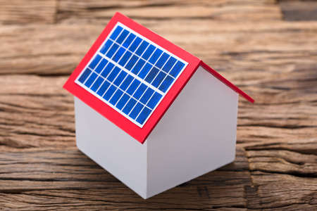 Closeup of solar panel on model home at wooden tableの写真素材