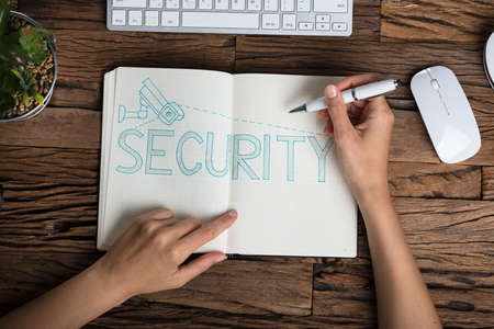 Elevated View Of A Human Hand With Security Text On Notebook Over Wooden Deskの写真素材