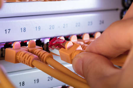 Cropped image of hand connecting network cable plug to server