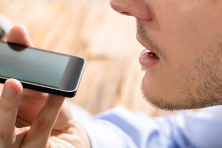 Close-up Of A Businessman Using Voice Assistant On Mobile Phoneの写真素材