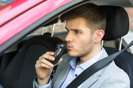 Close-up Of A Young Man Sitting Inside Car Taking Alcohol Testの写真素材