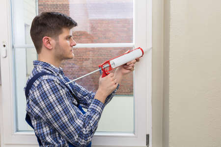 Side View Of A Young Male Worker Applying Glue With Silicone Gunの写真素材