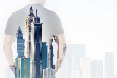 Double exposure of businessman with hands in pockets and office buildings