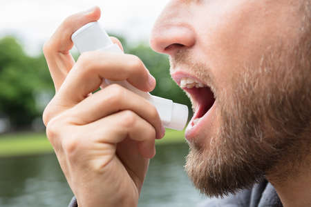 Close-up Of Beard Man Using Asthma Inhaler For Being Healthyの写真素材