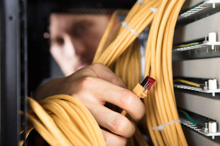 Close-up Of Engineer Plugging Cables Into Server In Data Centerの写真素材