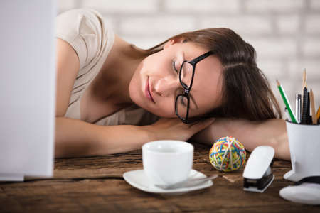 Young Businesswoman Wearing Eyeglasses Napping In Officeの写真素材