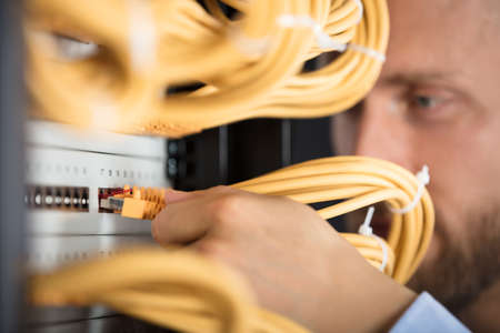 Close-up Of Engineer Plugging Cables Into Server In Data Centerの写真素材