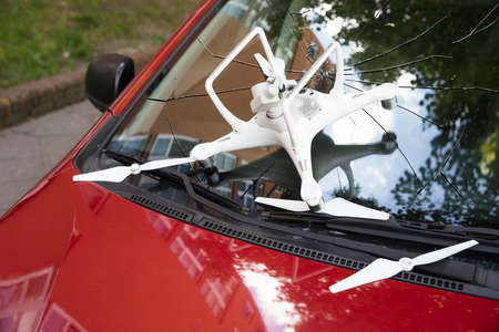 Closeup of damaged white drone on broken car windshieldの写真素材