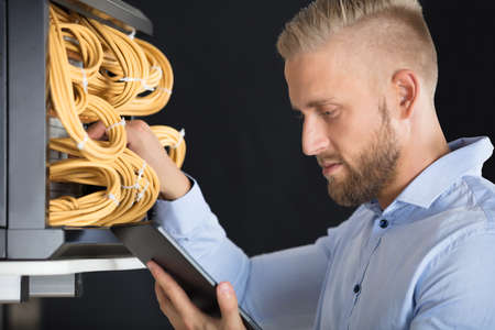 Close-up Of Young Male Technician Checking Server's Wires In Data Center