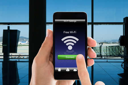 Cropped image of person's hands using free WiFi on smart phone in airportの写真素材