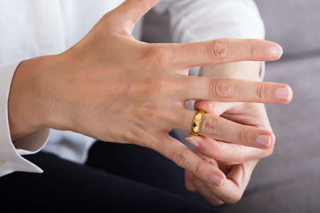 Close-up Of A Woman Putting On A Shiny Gold Ring On Finger