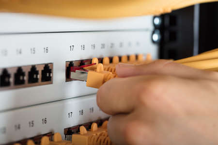 Close-up Of Engineer Plugging Cables Into Server In Data Centerの写真素材
