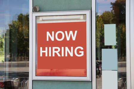 Closeup of now hiring sign outside modern office buildingの写真素材